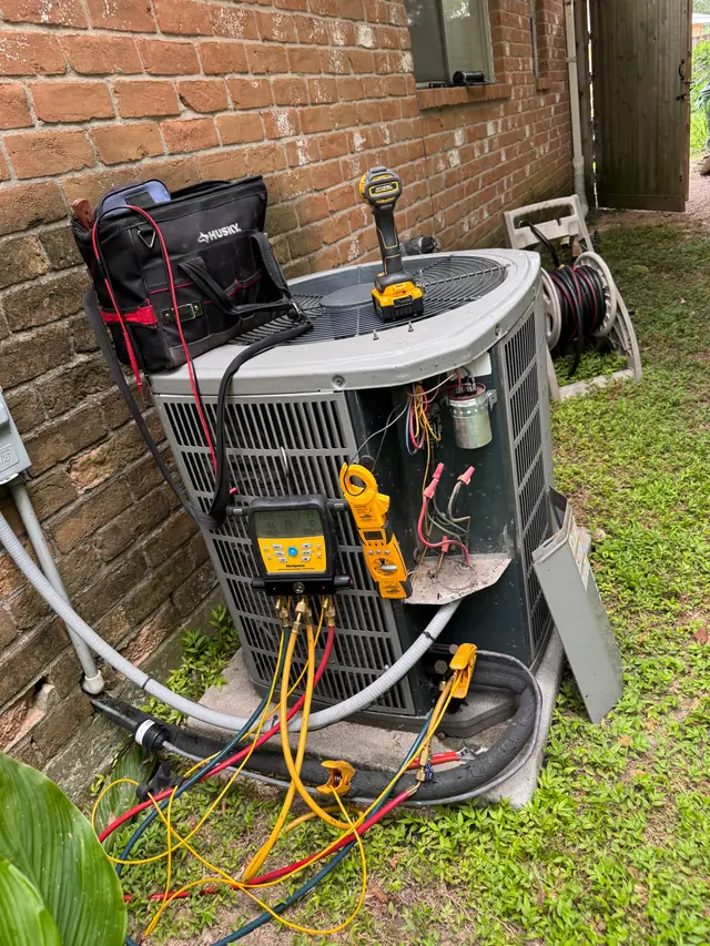 Digital manifold gauges and clamp meter on a residential condenser