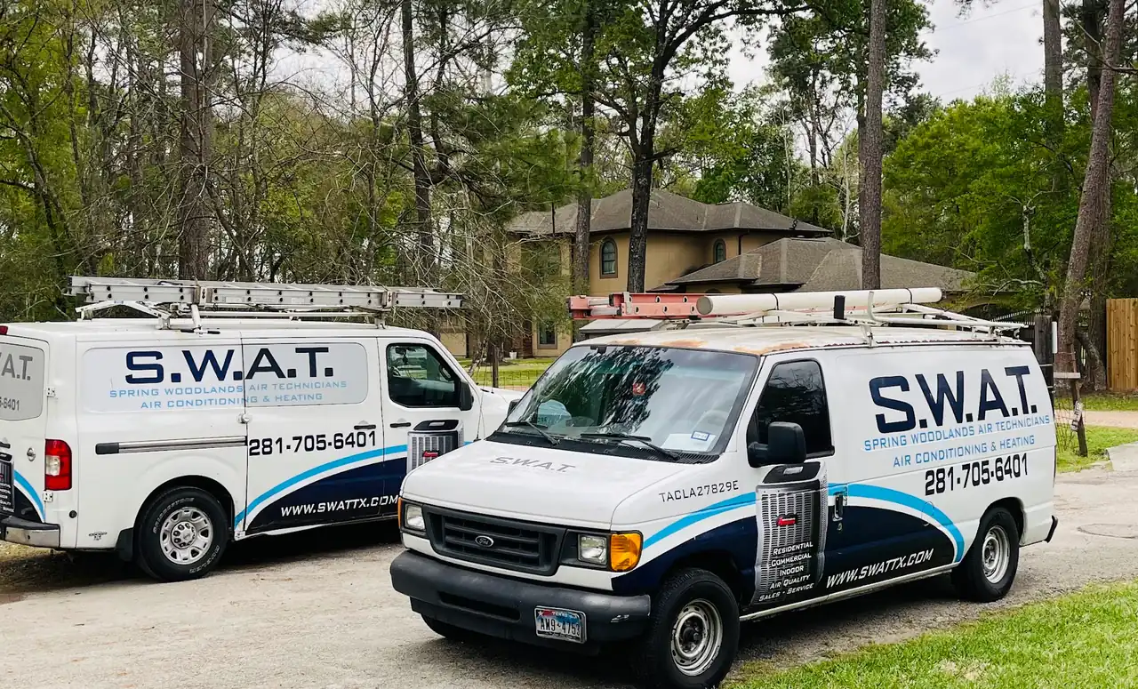 Two S.W.A.T service vans parked under pines in Spring, Texas